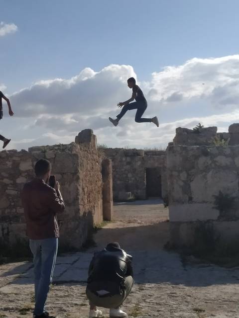 Man performing a jump between stone ruins.