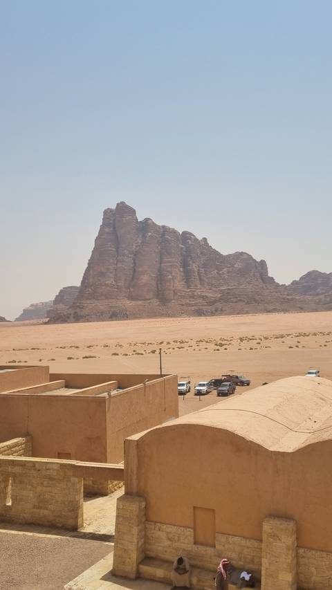       Desert landscape with rock formations and tourists exploring.
  