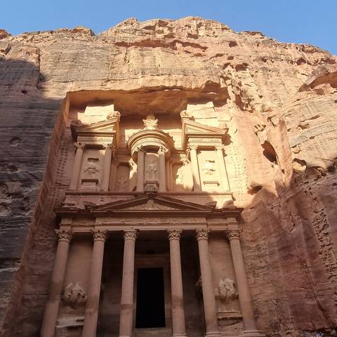       Ancient stone building facade with columns and intricate carvings.
  