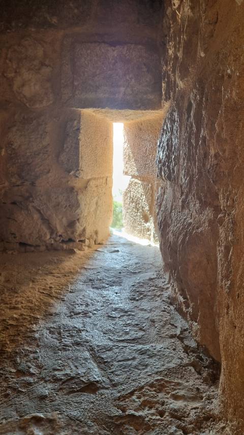       Stone wall with small window opening letting in light.
  