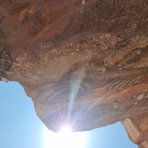 Sunlit rocky surface with erosion patterns.