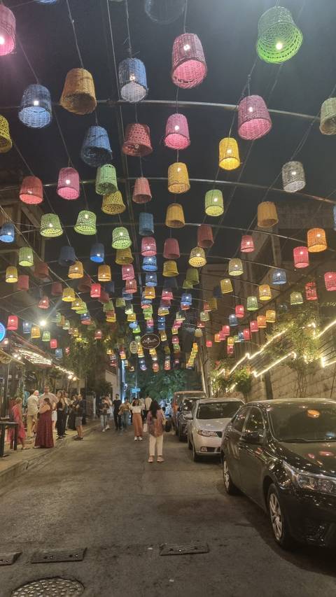       Colorful lanterns suspended over a lively street scene at night.
  