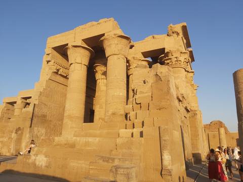 Ancient Egyptian temple with hieroglyphs and columns in bright sunlight.
