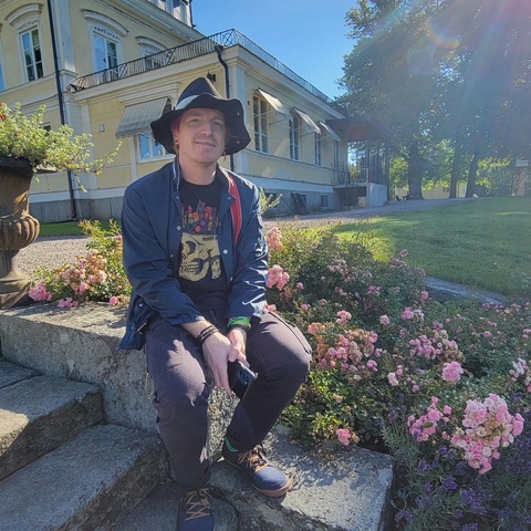       Person sitting on a stone ledge in a garden area.
  