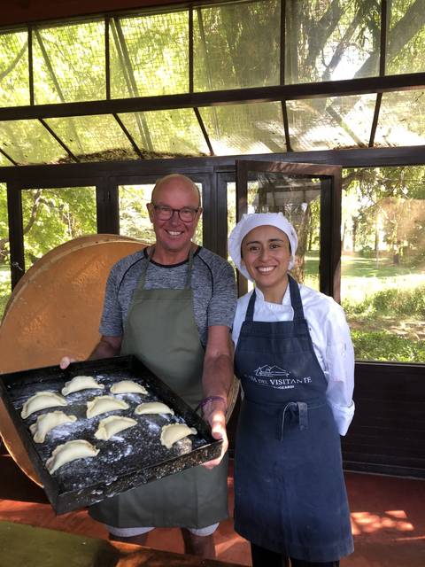 Two people posing with a tray of uncooked pastries in a kitchen setting.