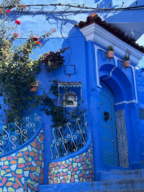 Vibrant blue building with plants and patterns in Chefchaouen.