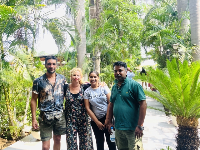       Group of people posing outside amidst greenery.
  