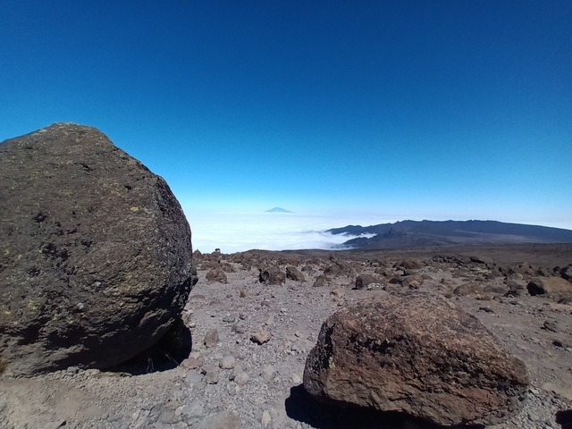 A rocky landscape with a vast view of clouds and distant mountains.