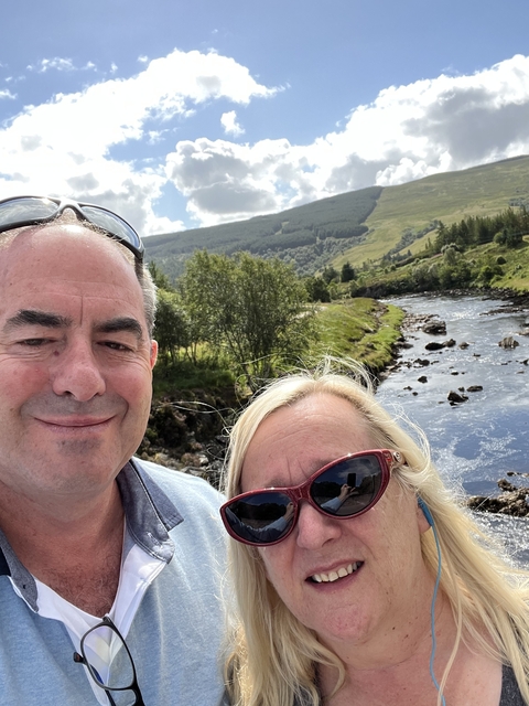Selfie of a couple with a scenic river and hills backdrop