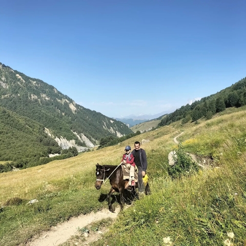       People on horseback in a scenic valley landscape.
  