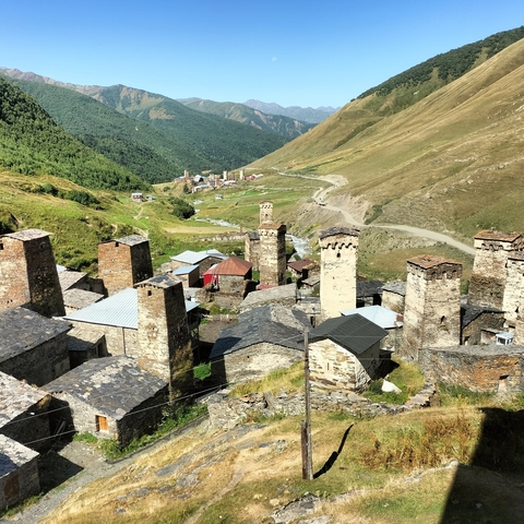       Historic village with several towers in a mountain landscape.
  