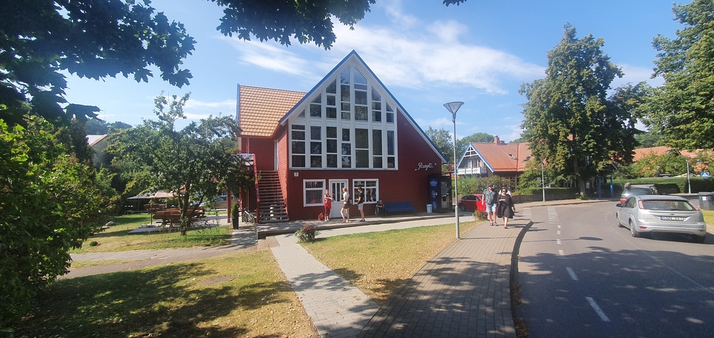 A wooden building on a sunny day, surrounded by trees.