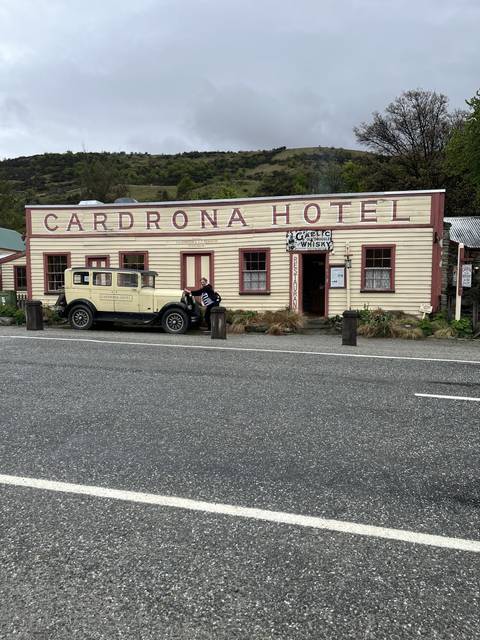       A historic hotel building with a classic car parked in front.
  
