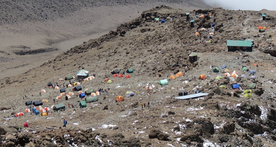 Aerial view of a campsite with colorful tents in a rocky landscape.