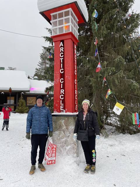Two people standing at the Arctic Circle landmark.