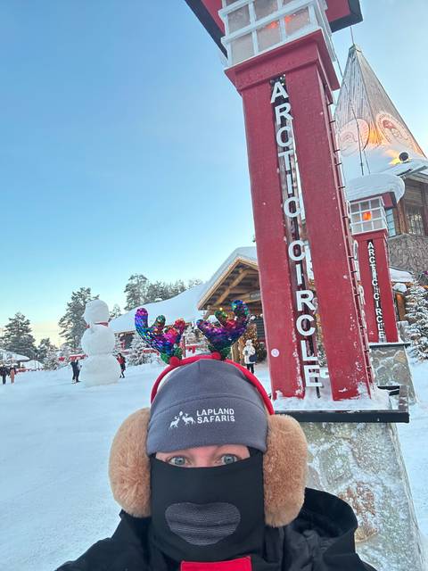 Person bundled in warm clothing near a sign in the snow.