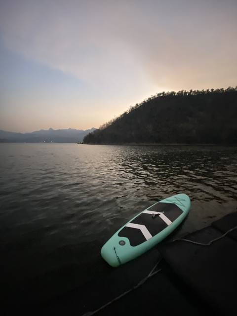       A paddleboard on a calm body of water during twilight.
  