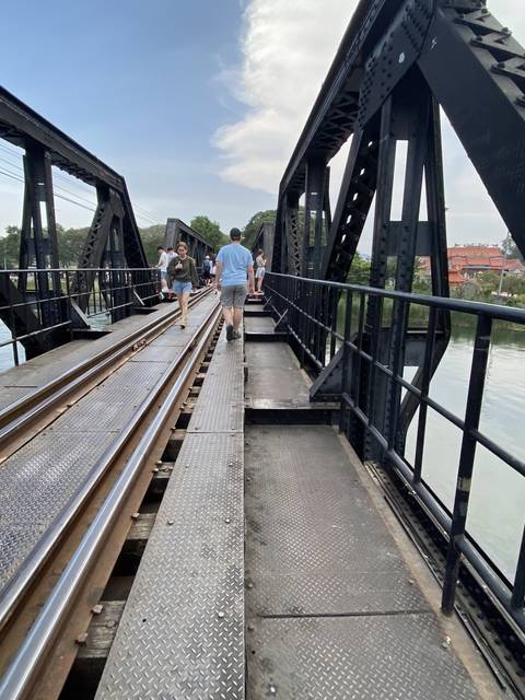       People walking on a metal bridge.
  