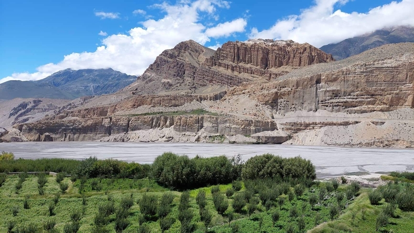 Cliffs and rock formations near a river with greenery.
