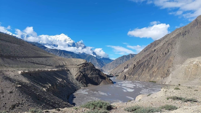 A river flowing through a mountainous valley with snow peaks.
