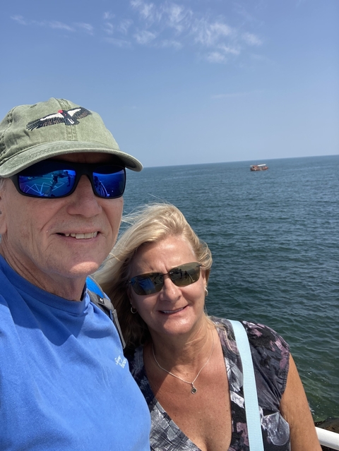 Two people on a boat with water and sky in the background.