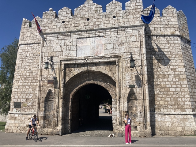 Historic stone gate with people walking nearby.