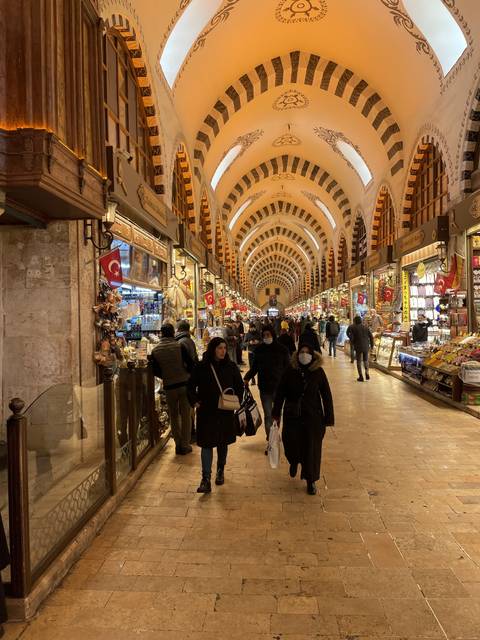 Interior of a busy marketplace with decorations and people shopping.