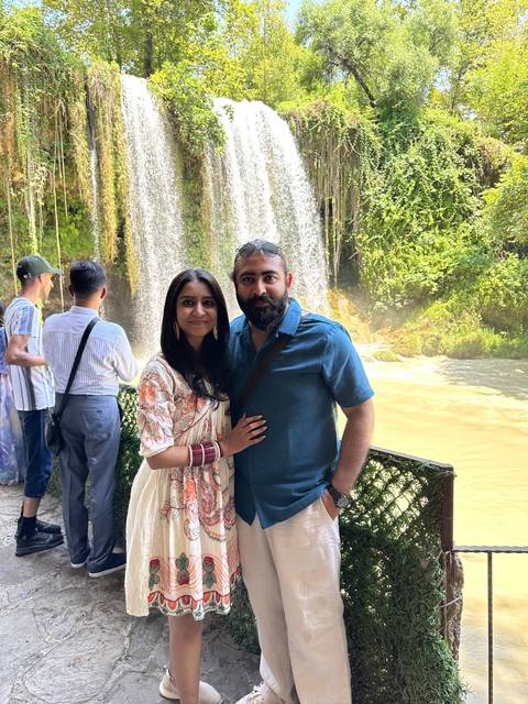       Couple posing in front of a waterfall with lush greenery.
  