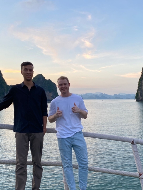 Two people posing with a scenic bay and karst landscape in the background.