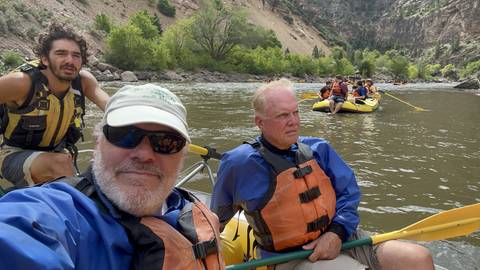       Rafting trip with people smiling and paddling.
  