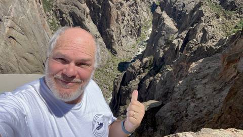 Person pointing at a canyon landscape.