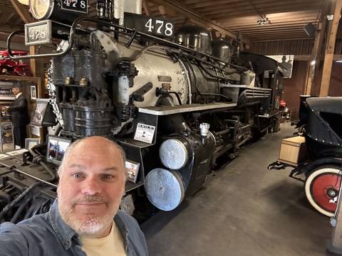       Person next to a large engine in a museum setting.
  