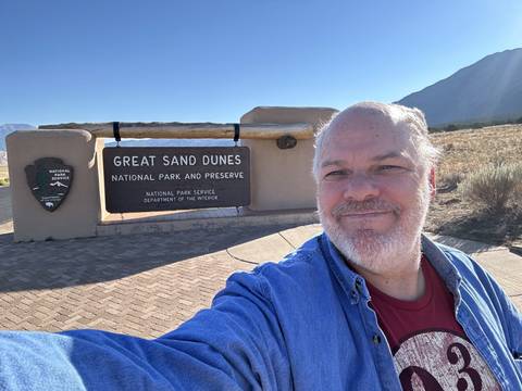       Person in front of a Great Sand Dunes National Park sign.
  