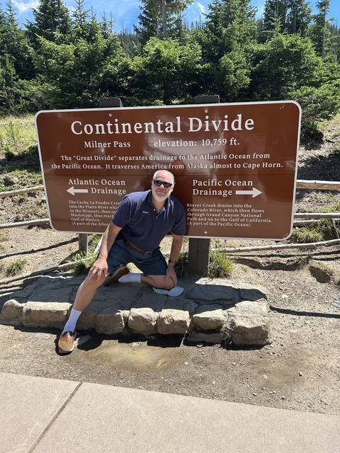       Man posing with a sign at the Continental Divide.
  