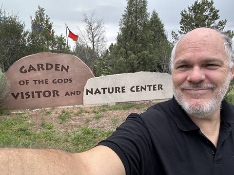       Man with the Garden of the Gods visitor center sign.
  
