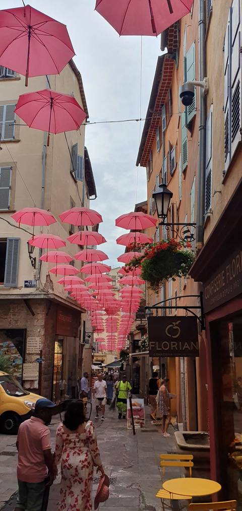 Street with pink umbrellas suspended above.