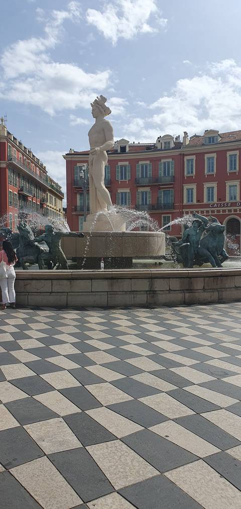       Fountain in a plaza surrounded by buildings.
  
