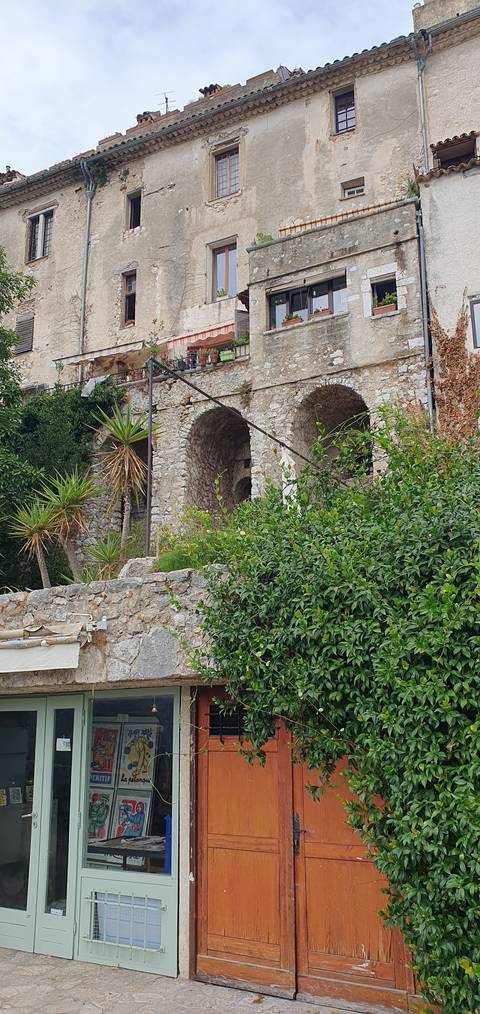       Old stone building with overgrown foliage.
  