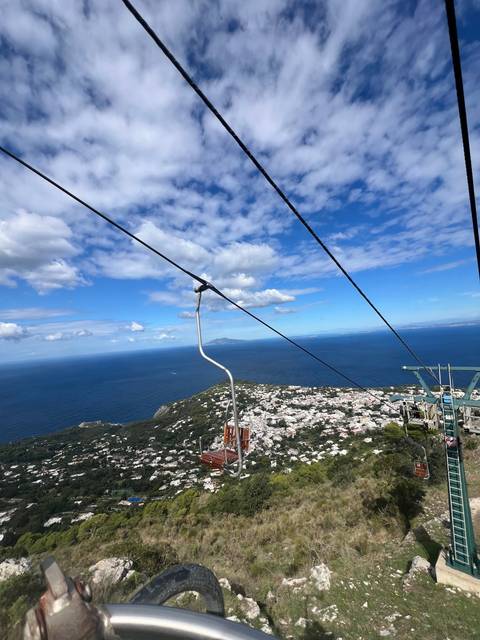 Ski lift view overlooking a city and the ocean.