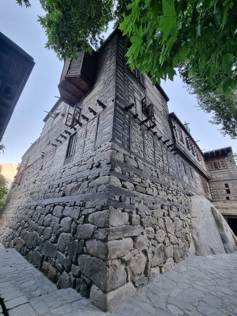 Traditional stone building with windows, surrounded by trees.