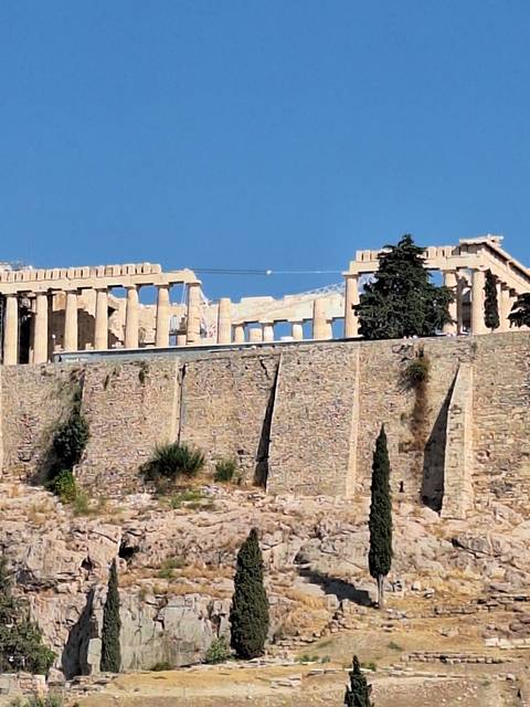 Ruins on a hillside with a clear blue sky.