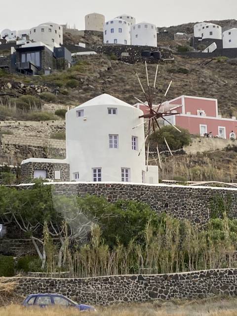       Windmill on a hillside with white buildings.
  