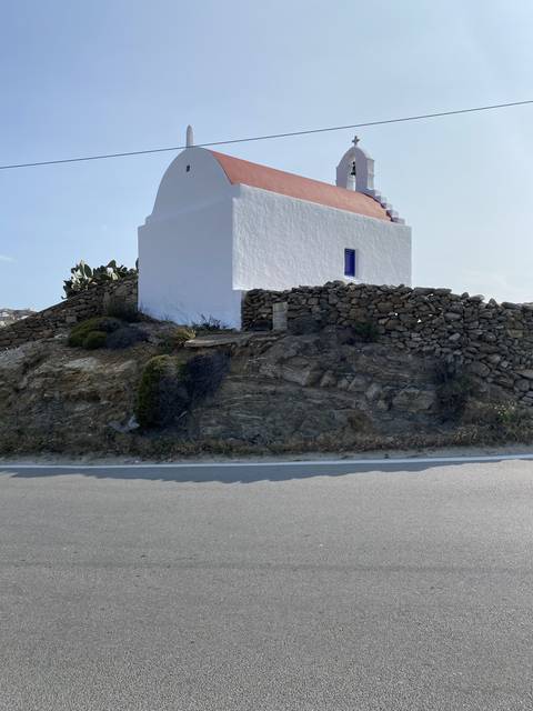       White church with a red roof on a roadside.
  