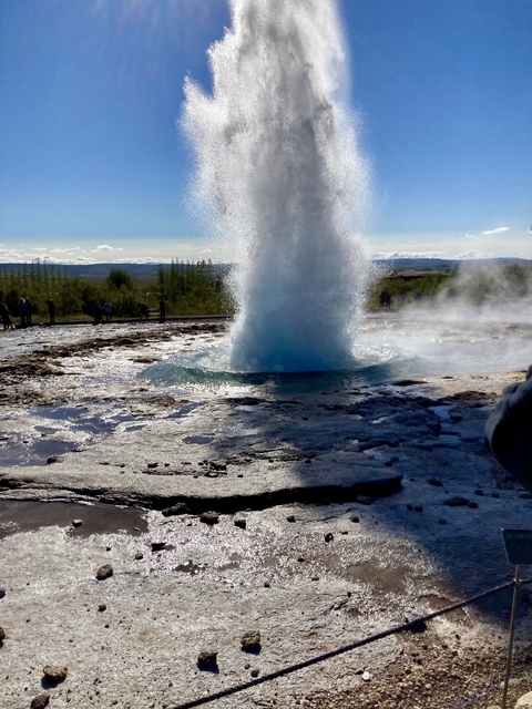       Geyser erupting with water spraying upward in a vast landscape.
  