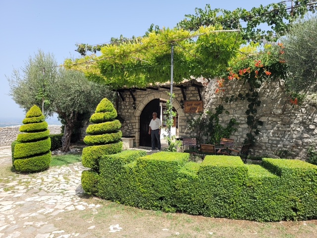Man standing outside a doorway in a lush garden.