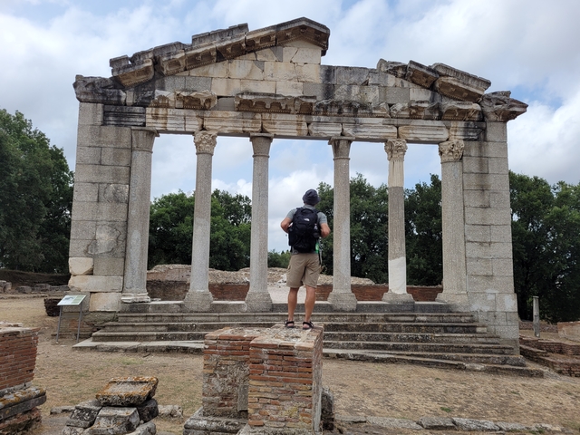       Man standing in front of a historic ruin with tall columns.
  