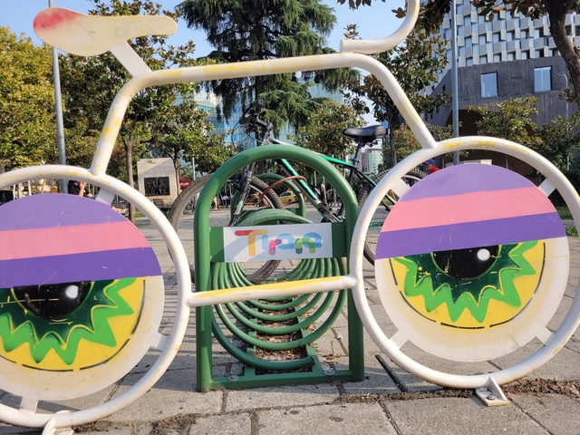       Colorful bicycle rack with abstract patterns and a logo in a public area.
  