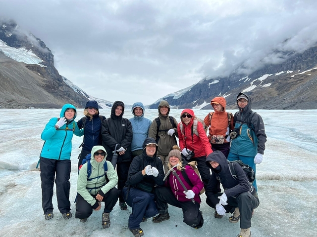 Group of people on a glacier with mountains in the back.
