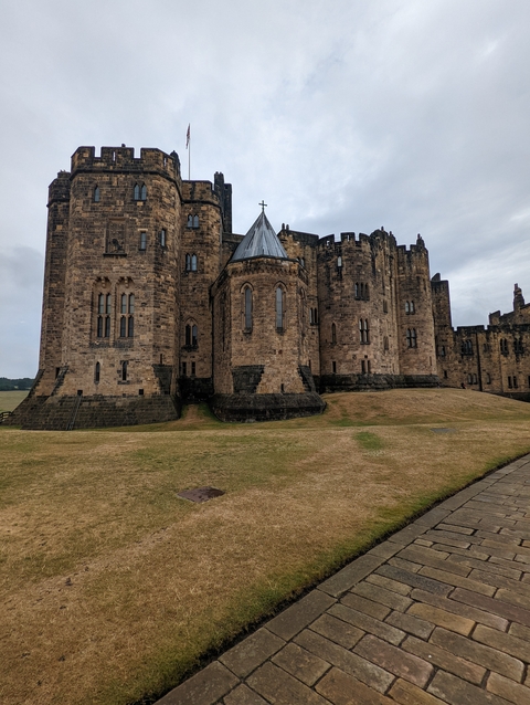 Stone castle with a sloped grassy yard.