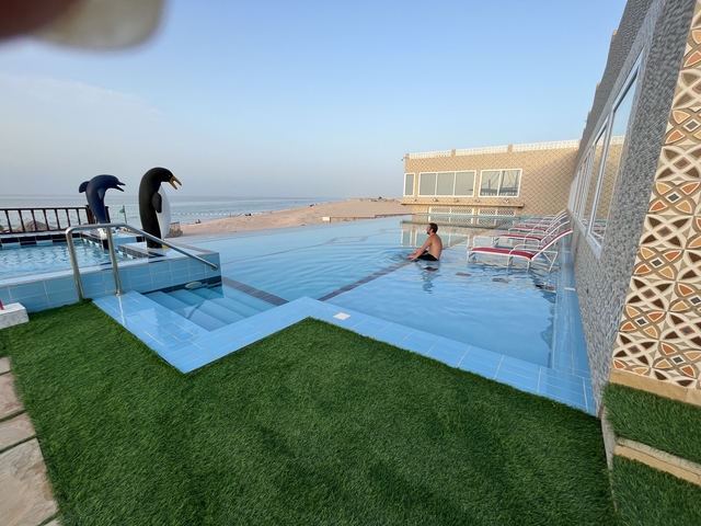       Man swimming in an infinity pool overlooking the sea.
  